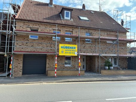 Sanierungsgebäude mit Gerüst und großem gelben Schild auf der Vorderseite.