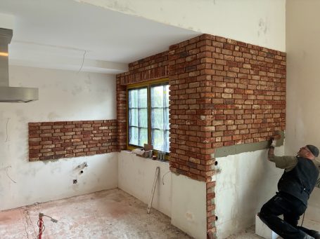 Ein Handwerker klebt Klinkerriemchen in einer umgestalteten Küche.