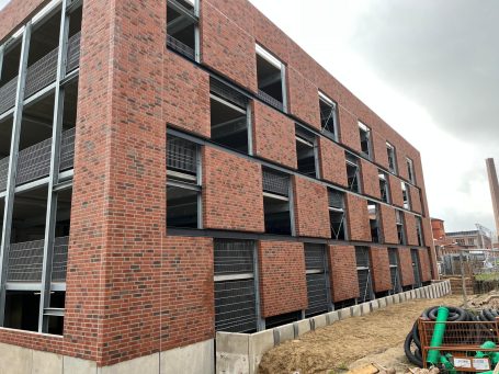 Neugebautes Backsteingebäude mit offenen Fenstern und unvollendeter Fassade.